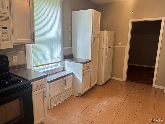 6624 Bartmer Ave, University City, MO 63130 - kitchen with white appliances, dark countertops, light tile patterned floors, and white cabinetry
