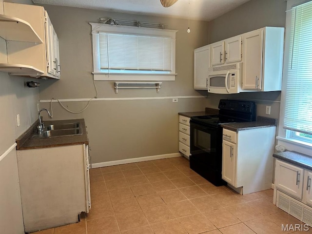 6624 Bartmer Ave, University City, MO 63130 - kitchen with white microwave, electric range, dark countertops, light tile patterned flooring, and white cabinets