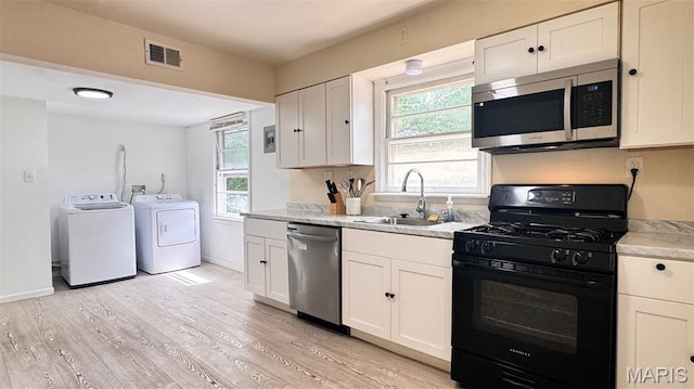 3400 Adie Rd, Saint Ann, MO 63074 - kitchen featuring stainless steel appliances, washing machine and clothes dryer, light countertops, white cabinetry, and light wood finished floors