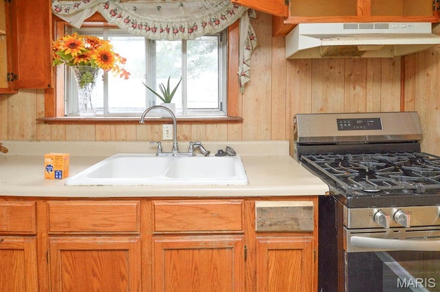 601 Mcbride Ave, Dupo, IL 62239 - kitchen with gas stove, under cabinet range hood, light countertops, wood walls, and brown cabinetry