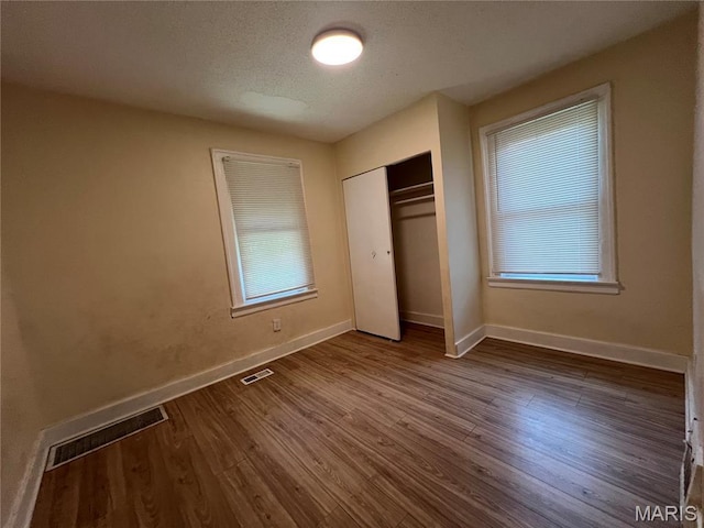 5502 Helen Ave, Saint Louis, MO 63136 - unfurnished bedroom with dark wood-style floors, a closet, and a textured ceiling