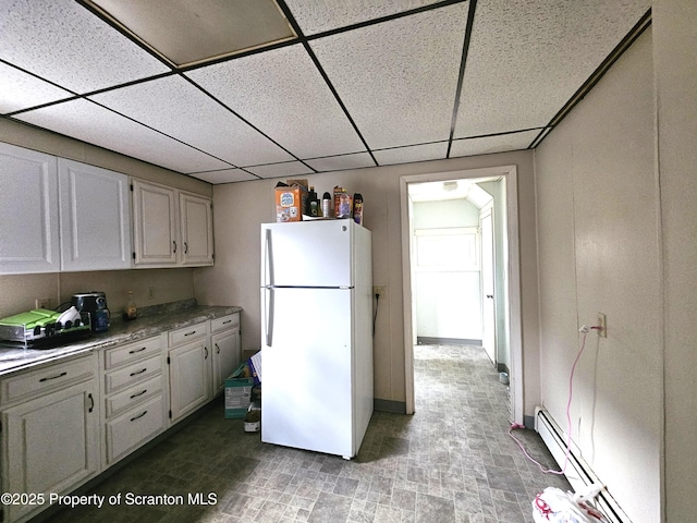 kitchen featuring white cabinetry, white fridge, a drop ceiling, and baseboard heating