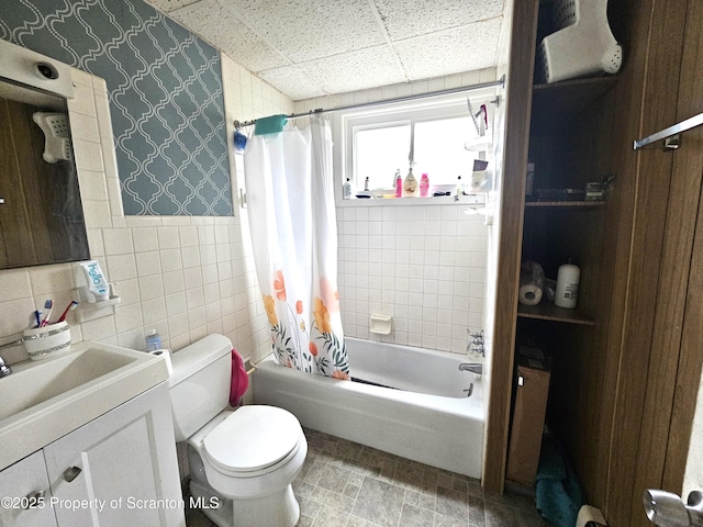 full bathroom with tile walls, vanity, toilet, shower / bath combo, and a drop ceiling