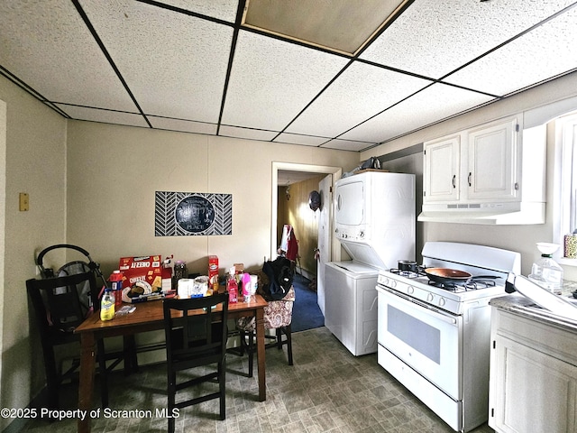 kitchen with stacked washer / drying machine, a paneled ceiling, white cabinets, and white range with gas stovetop