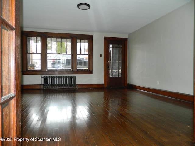 empty room with radiator, baseboards, and hardwood / wood-style flooring