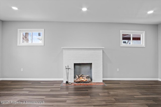 unfurnished living room featuring a brick fireplace and dark hardwood / wood-style floors