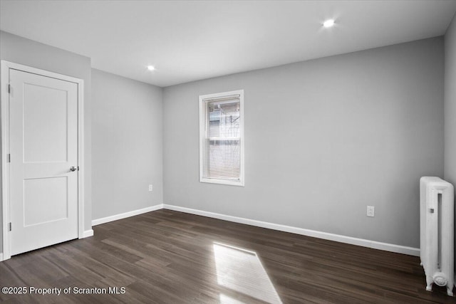 empty room with radiator and dark wood-type flooring