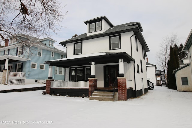 snow covered rear of property featuring covered porch