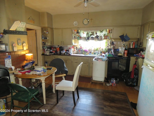 kitchen with cream cabinets, black range, white refrigerator, ceiling fan, and dark hardwood / wood-style floors