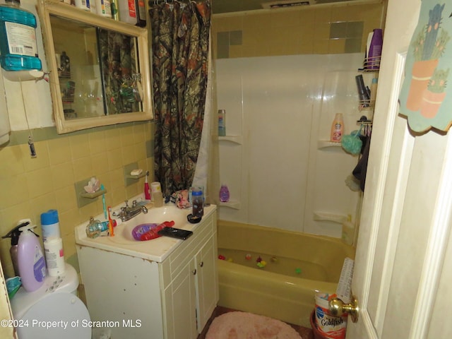 full bathroom featuring toilet, decorative backsplash, shower / tub combo with curtain, vanity, and tile walls