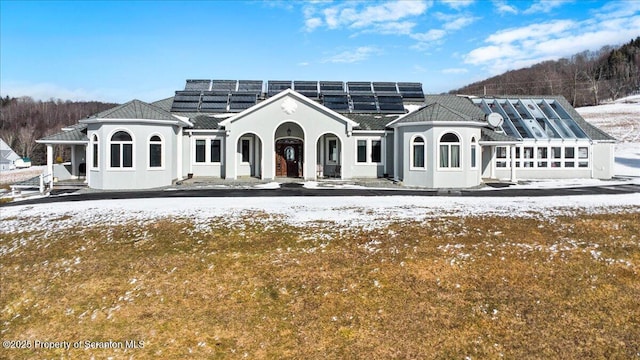 snow covered back of property with solar panels