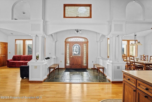 foyer featuring decorative columns, a high ceiling, and light wood-type flooring