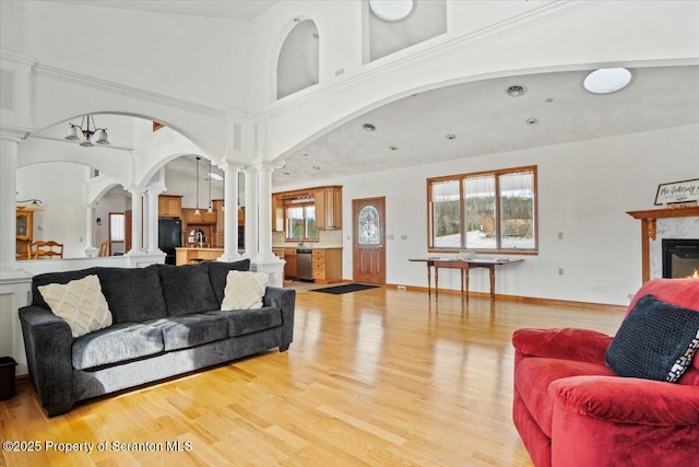 living room featuring a high ceiling, light hardwood / wood-style flooring, and ornate columns