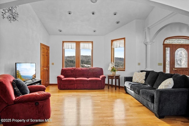 living room with lofted ceiling, light hardwood / wood-style floors, and ornate columns