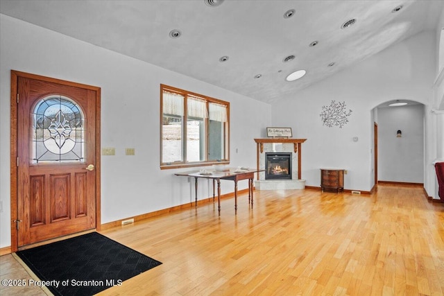 foyer entrance featuring light hardwood / wood-style flooring, a high end fireplace, and lofted ceiling