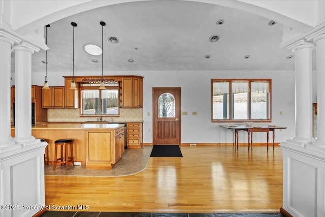 kitchen with hanging light fixtures, light hardwood / wood-style flooring, sink, and ornate columns