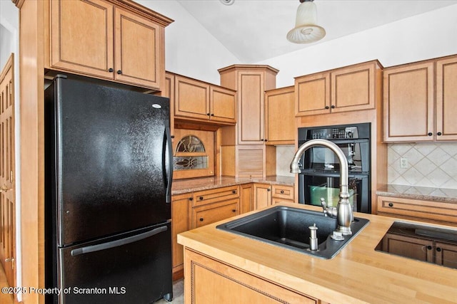 kitchen featuring vaulted ceiling, wood counters, sink, backsplash, and black appliances