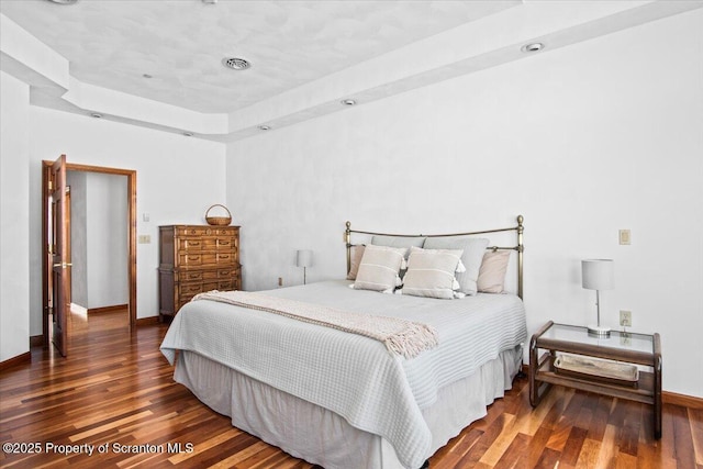 bedroom featuring a tray ceiling and dark hardwood / wood-style floors