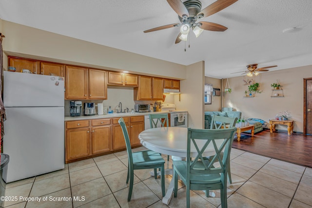 kitchen featuring sink, light tile patterned flooring, white appliances, and a textured ceiling