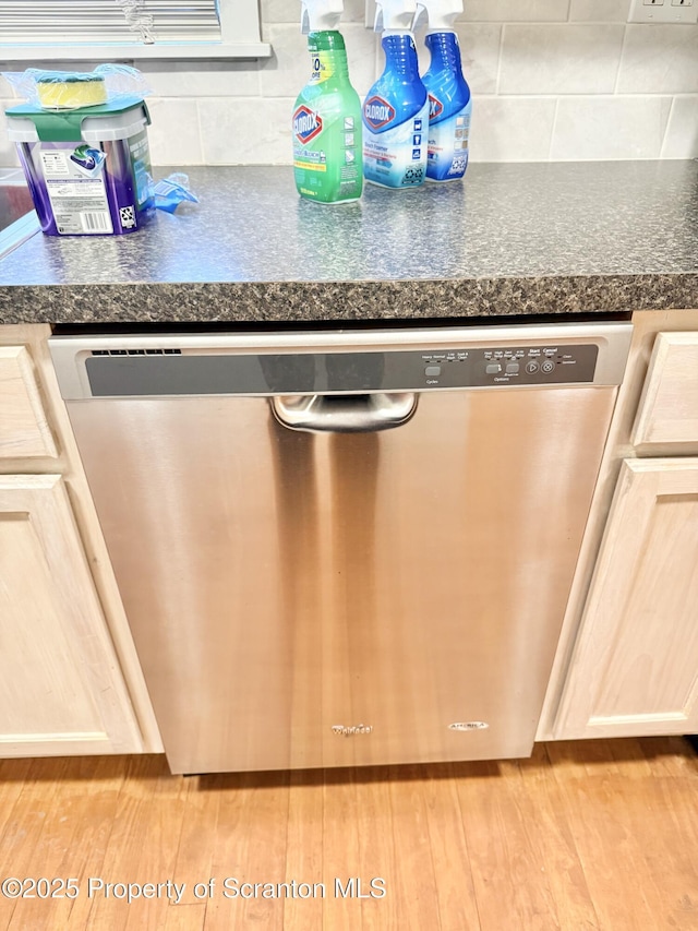 interior details featuring light brown cabinets, stainless steel dishwasher, light wood-type flooring, and tasteful backsplash