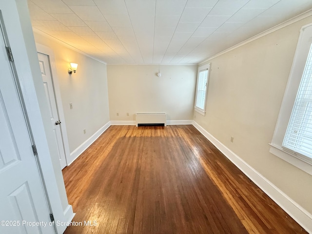 spare room with wood-type flooring, radiator, and ornamental molding