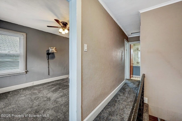 hall featuring crown molding, baseboards, and carpet floors
