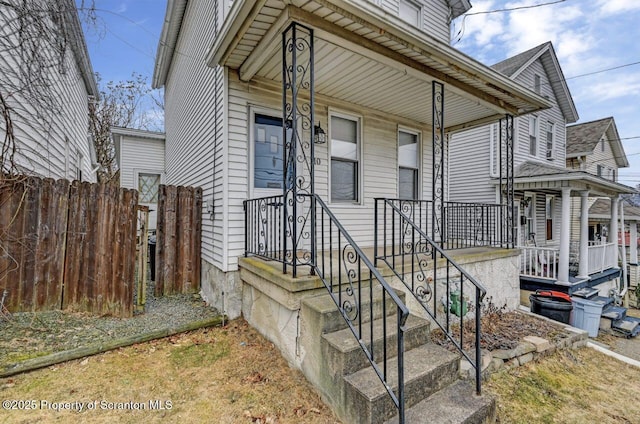 doorway to property featuring a porch and fence