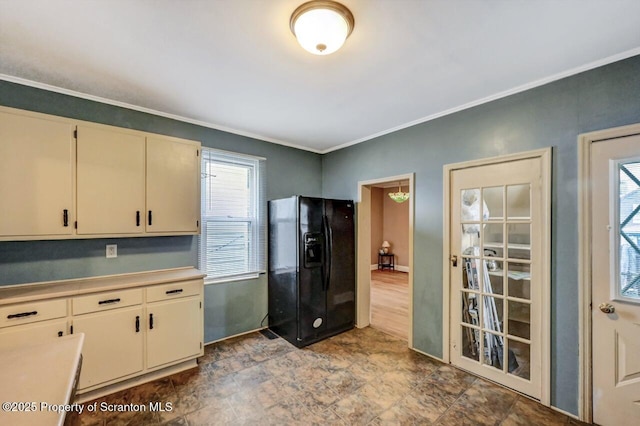 kitchen featuring cream cabinetry, ornamental molding, black refrigerator with ice dispenser, and light countertops