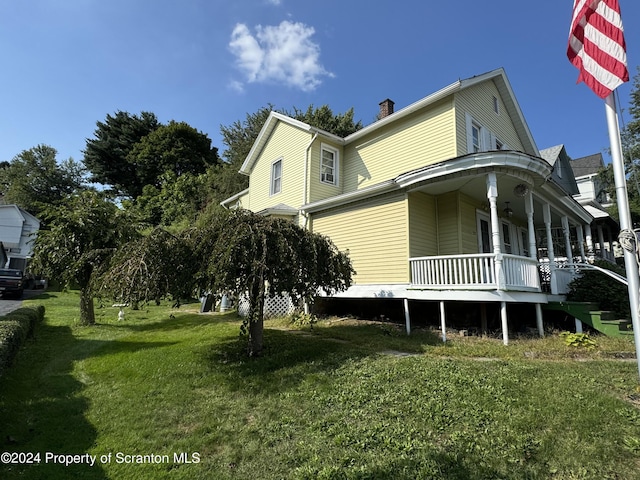 view of side of property with a porch and a lawn