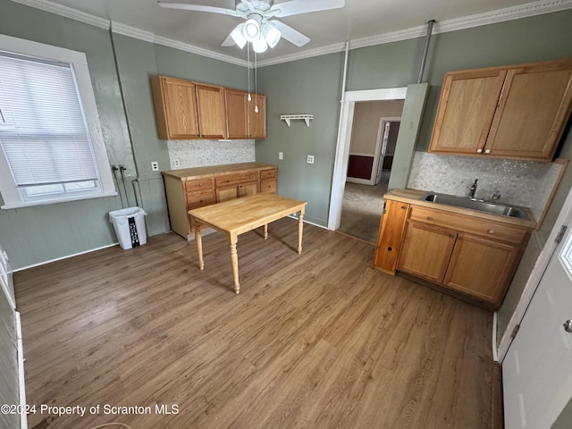 kitchen featuring ceiling fan, sink, crown molding, light hardwood / wood-style floors, and decorative backsplash