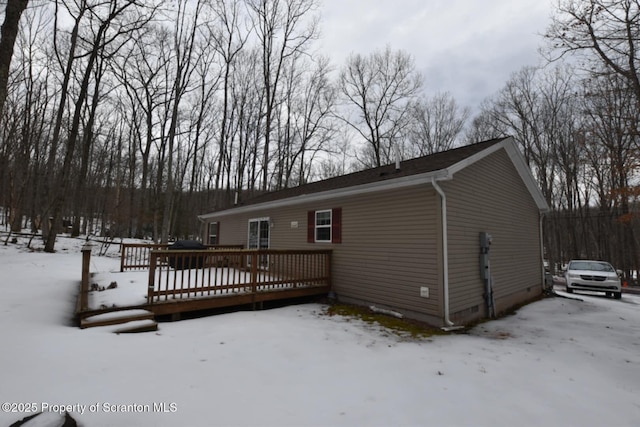 snow covered back of property with crawl space and a wooden deck