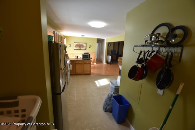 kitchen with brown cabinetry and freestanding refrigerator