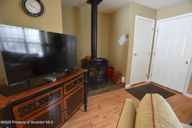 living area featuring wood finished floors, a wood stove, and baseboards