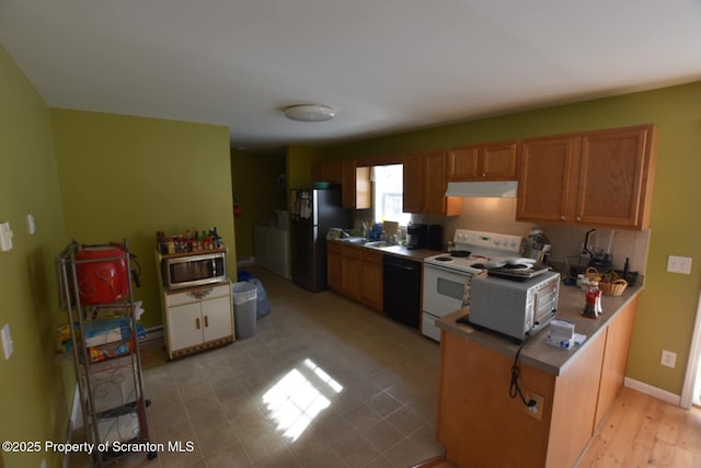 kitchen featuring under cabinet range hood, stainless steel appliances, baseboards, light countertops, and brown cabinetry