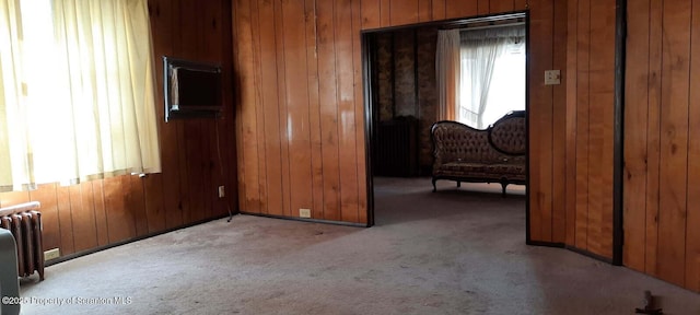 carpeted bedroom featuring radiator and wooden walls