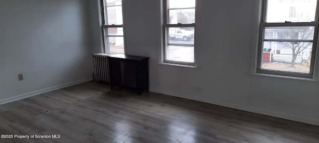 spare room with radiator heating unit and dark wood-type flooring