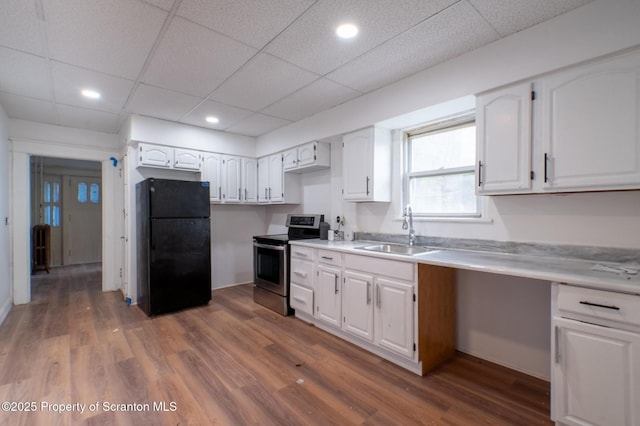 kitchen with freestanding refrigerator, white cabinets, stainless steel electric stove, and a sink
