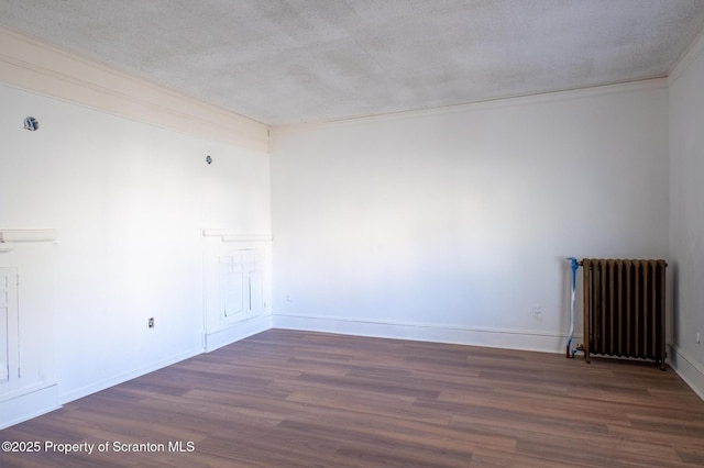 spare room featuring baseboards, a textured ceiling, radiator, and wood finished floors