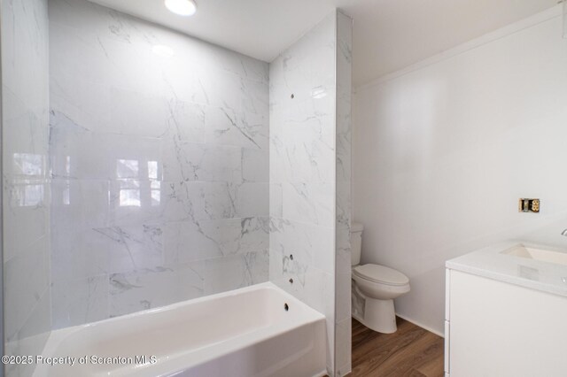 bathroom featuring vanity, washtub / shower combination, wood finished floors, and toilet
