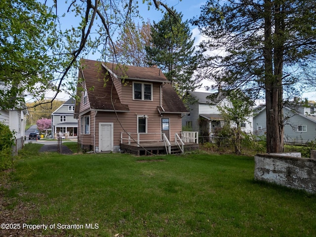 back of property with a yard, a deck, and a fenced backyard