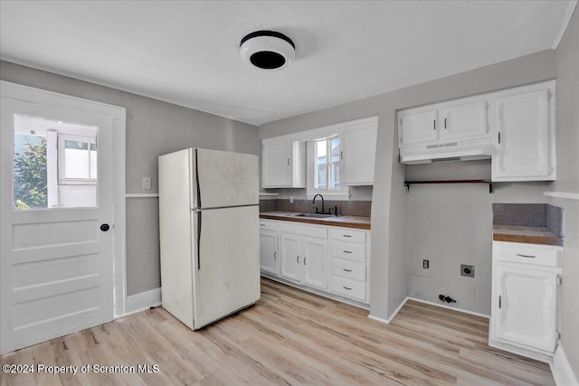 kitchen with white cabinets, white refrigerator, light hardwood / wood-style floors, and sink