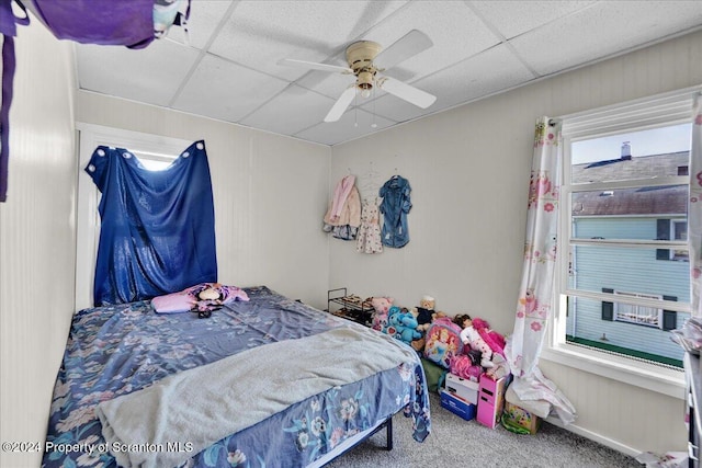 carpeted bedroom with a paneled ceiling, ceiling fan, and multiple windows