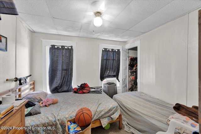 bedroom featuring a closet, ceiling fan, and a drop ceiling