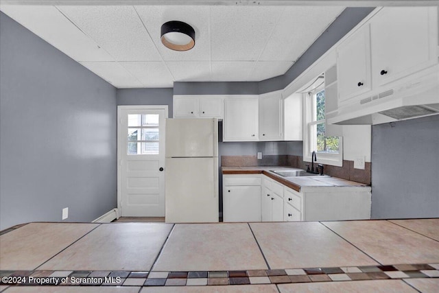 kitchen featuring tile countertops, sink, white cabinets, and white refrigerator