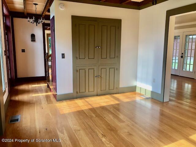 interior space with beamed ceiling, light hardwood / wood-style floors, wood ceiling, and an inviting chandelier