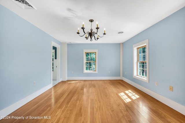 spare room with light hardwood / wood-style floors and a chandelier