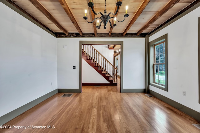 empty room featuring beam ceiling, wood ceiling, light hardwood / wood-style flooring, and an inviting chandelier