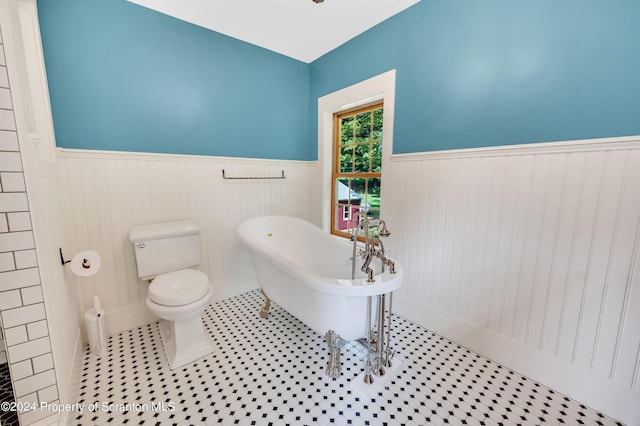 bathroom with tile patterned flooring, a bath, and toilet