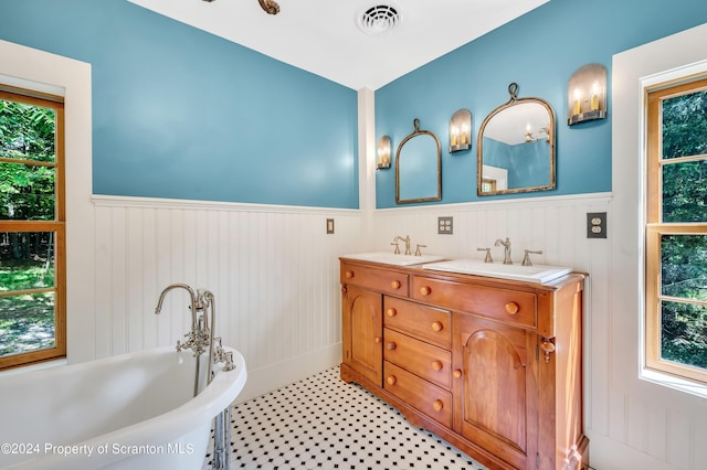 bathroom with a washtub, vanity, and tile patterned flooring