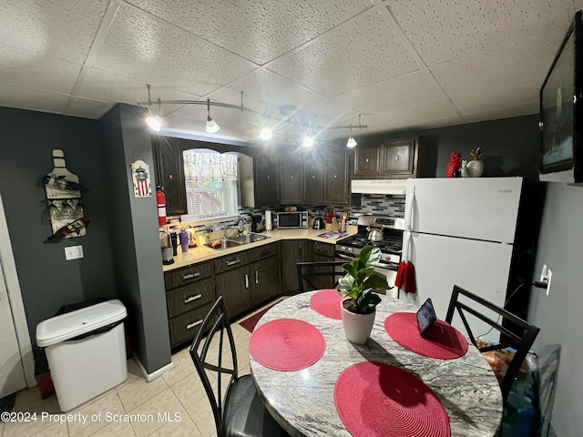 kitchen featuring a drop ceiling, sink, light tile patterned floors, appliances with stainless steel finishes, and dark brown cabinets